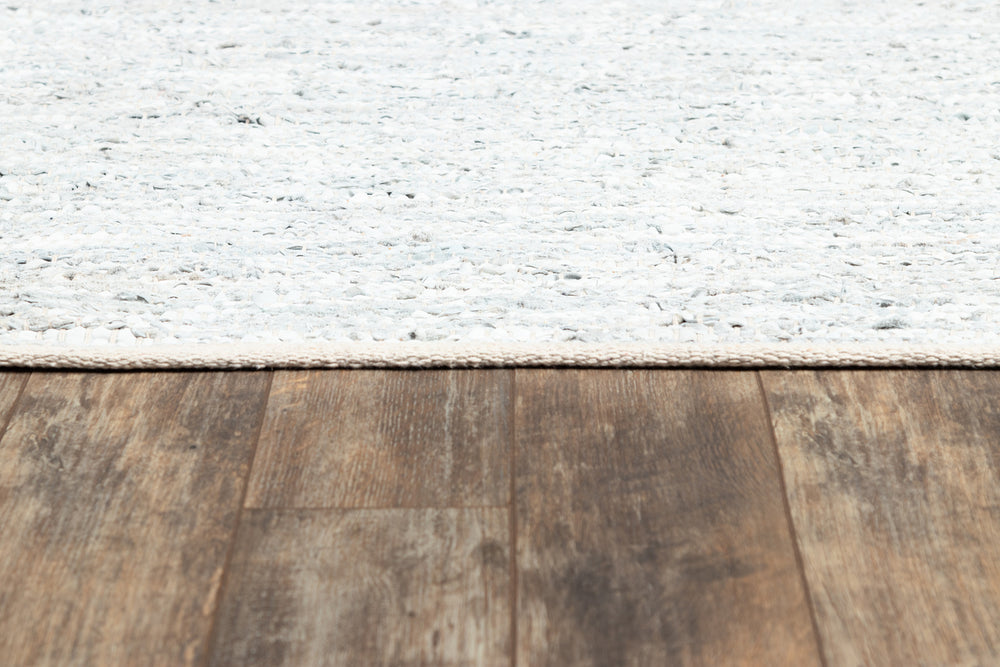 Lemieux et Cie Tézah Rug in ivory and soft grey handwoven recycled leather, low-profile rug shown on weathered wood flooring in natural light.