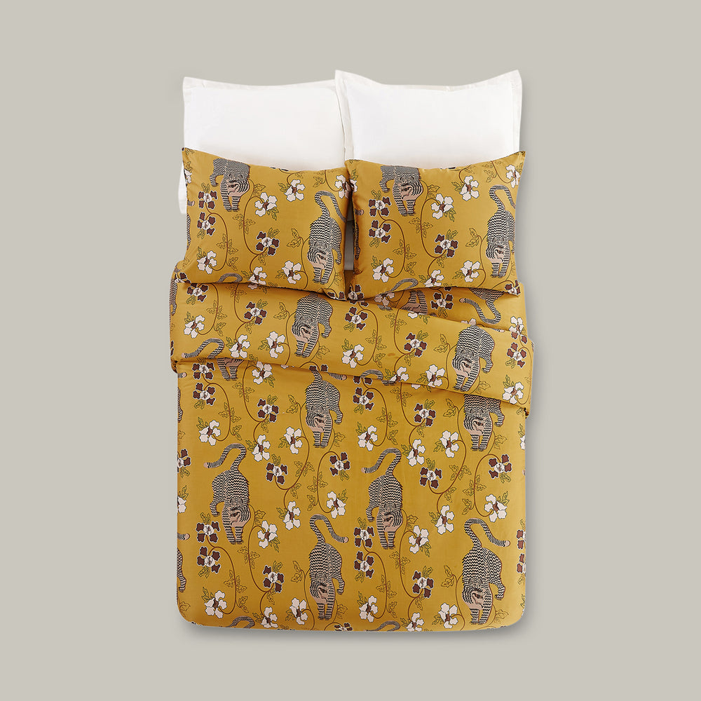 Lemieux et Cie Tiger 3-Piece Duvet Set in golden yellow with tiger and floral motif, cotton bedding styled with white pillows on neutral backdrop.