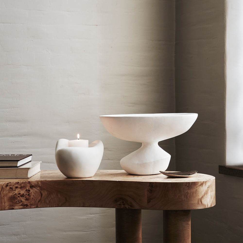Lemieux et Cie Ducoli Organic Bowl in white, sculptural vessel with curved pedestal base, styled on burl wood table with candle and books.
