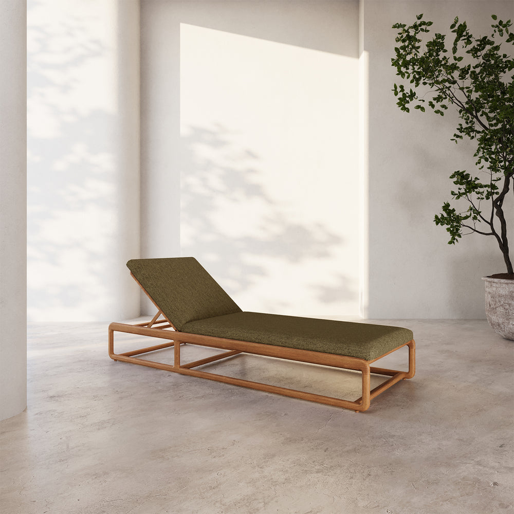 Lemieux et Cie Dock Teak Chaise Lounge with olive green cushion, low-profile frame on stone flooring in soft daylight with potted tree.