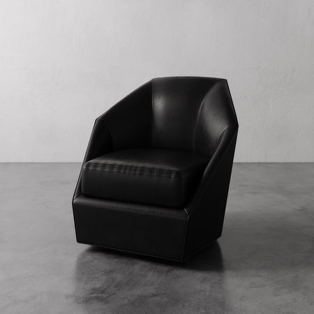 Lemieux et Cie Bijou Swivel Chair in black leather, geometric faceted form, shown on polished concrete floor against white wall.