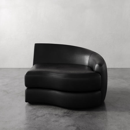 Lemieux et Cie Rulmann Right Arm Chair in black leather, sculptural curved lounge chair with rounded back on polished concrete floor.