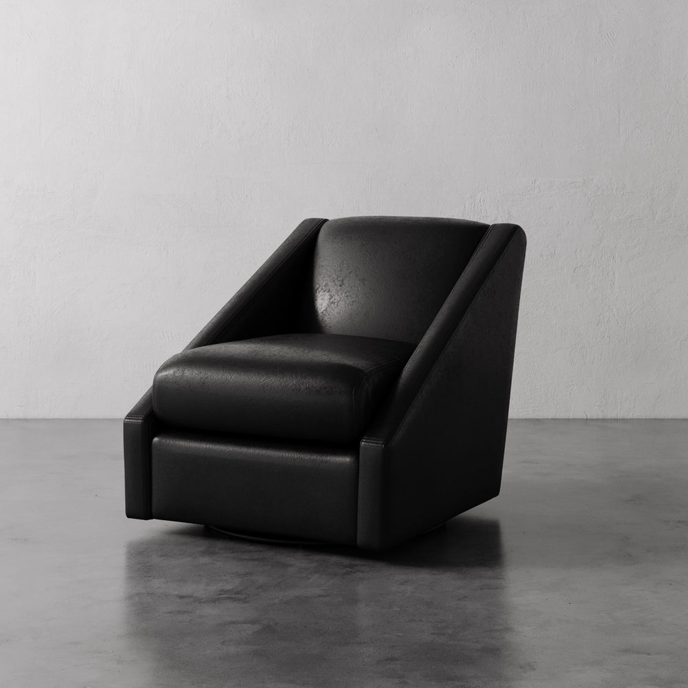 Lemieux et Cie Fontaine Swivel Chair in black, sculptural low-profile form with angled arms, shown on polished concrete floor against neutral plaster wall.