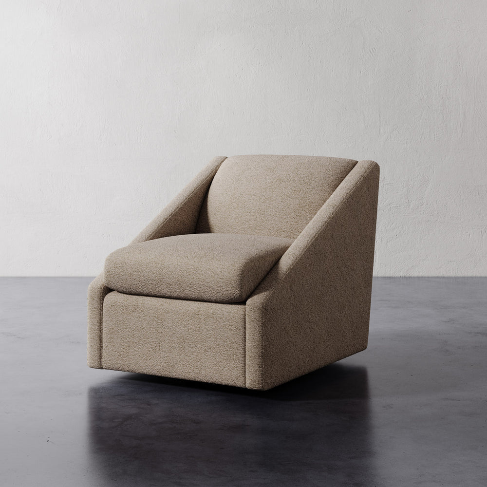 Lemieux et Cie Fontaine Swivel Chair in neutral upholstery, sculptural lounge chair with angled arms on dark stone floor and white walls