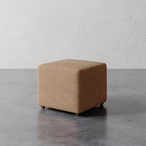 Lemieux et Cie Fabien 22" Square Ottoman in warm textured upholstery, low-profile accent piece on polished concrete floor against textured plaster walls.