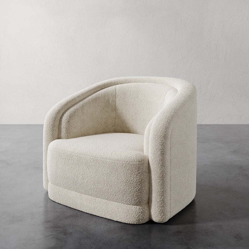 Lemieux et Cie Valence Swivel Chair in ivory bouclé, sculptural curved arms and rounded silhouette, shown on concrete floor against neutral walls.