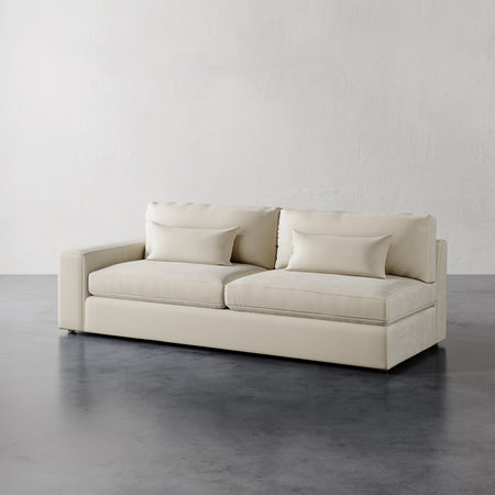 Lemieux et Cie Lacroix Left Arm Sofa in ivory, modular sofa with rectilinear form, shown on polished concrete flooring against textured white walls.