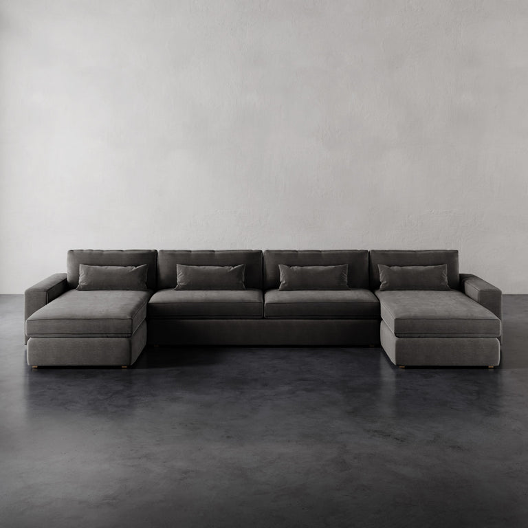 Lemieux et Cie Lacroix Sofa Chaise & A Half U-Sectional in charcoal, low-profile sectional with dual chaises on dark concrete floor, neutral plaster walls.