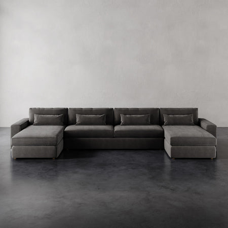 Lemieux et Cie Lacroix Sofa Chaise & A Half U-Sectional in charcoal, low-profile sectional with dual chaises on dark concrete floor, neutral plaster walls.