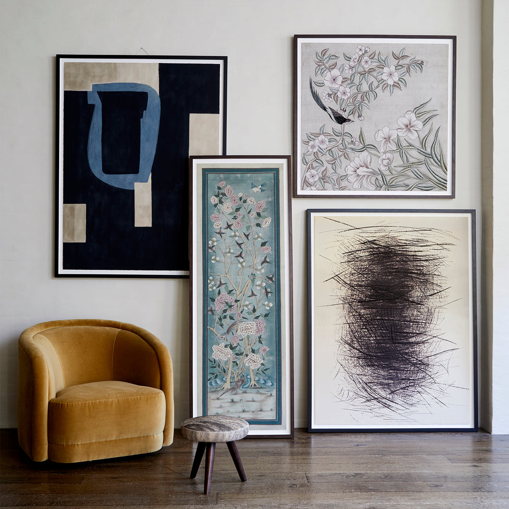 Lemieux et Cie Framing Add-On for Limited Edition Prints, framed artworks leaning against neutral wall beside warm gold chair, wood flooring.