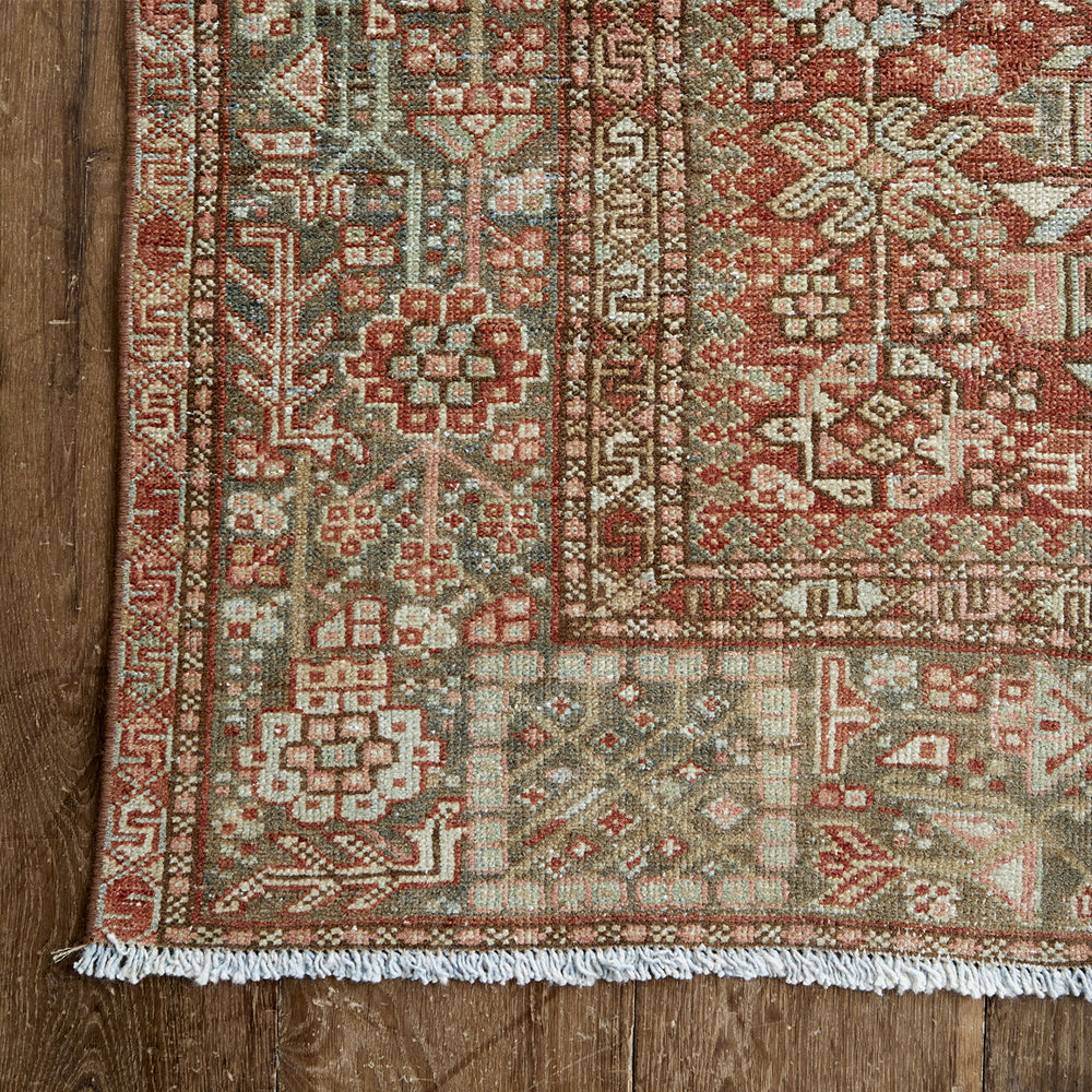 Lemieux et Cie Heriz Carpet in rich reds, blues and greens, vintage Persian rug with geometric angular motifs, shown on warm wood flooring.