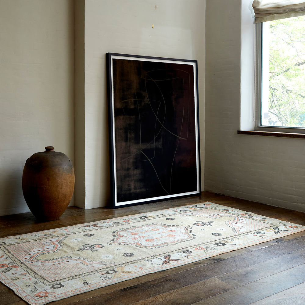 Lemieux et Cie Anatolian Village Rug in soft geometric pattern with coral and charcoal accents, vintage Turkish wool rug on wood floors beside ceramic vase and framed art in neutral sitting room