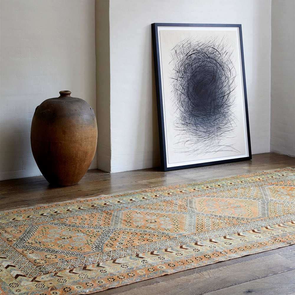 Lemieux et Cie Serab Runner in camel with geometric lozenge medallions, vintage Persian rug on wood floors beside ceramic vase and framed artwork against white walls.