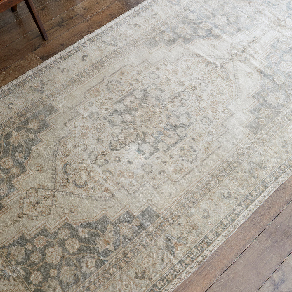 Lemieux et Cie Shiraz Rug in muted ivory, sage and tan with geometric medallion pattern, vintage Persian rug on aged wood flooring.