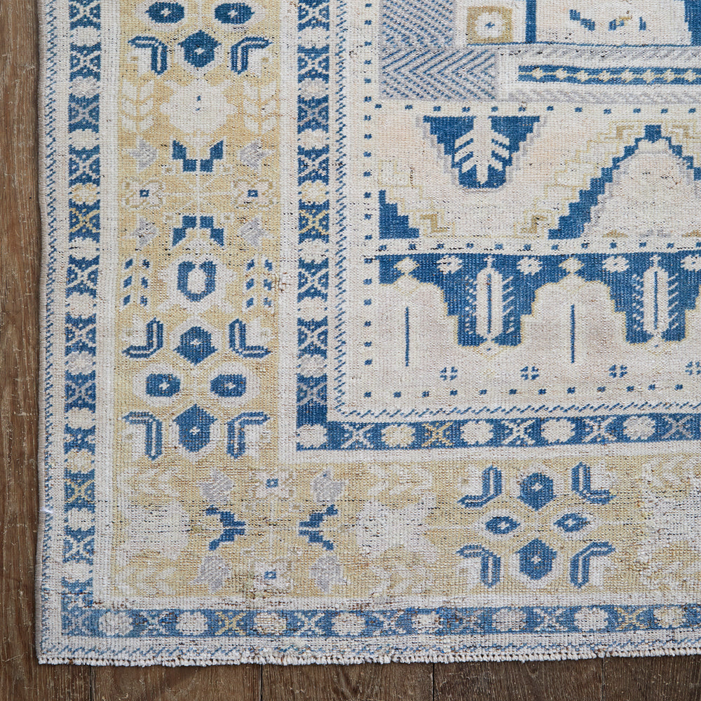 Lemieux et Cie Anatolian Village Rug in blue, tan and ivory handwoven wool, geometric motifs with worn patina, shown on weathered wood floors.