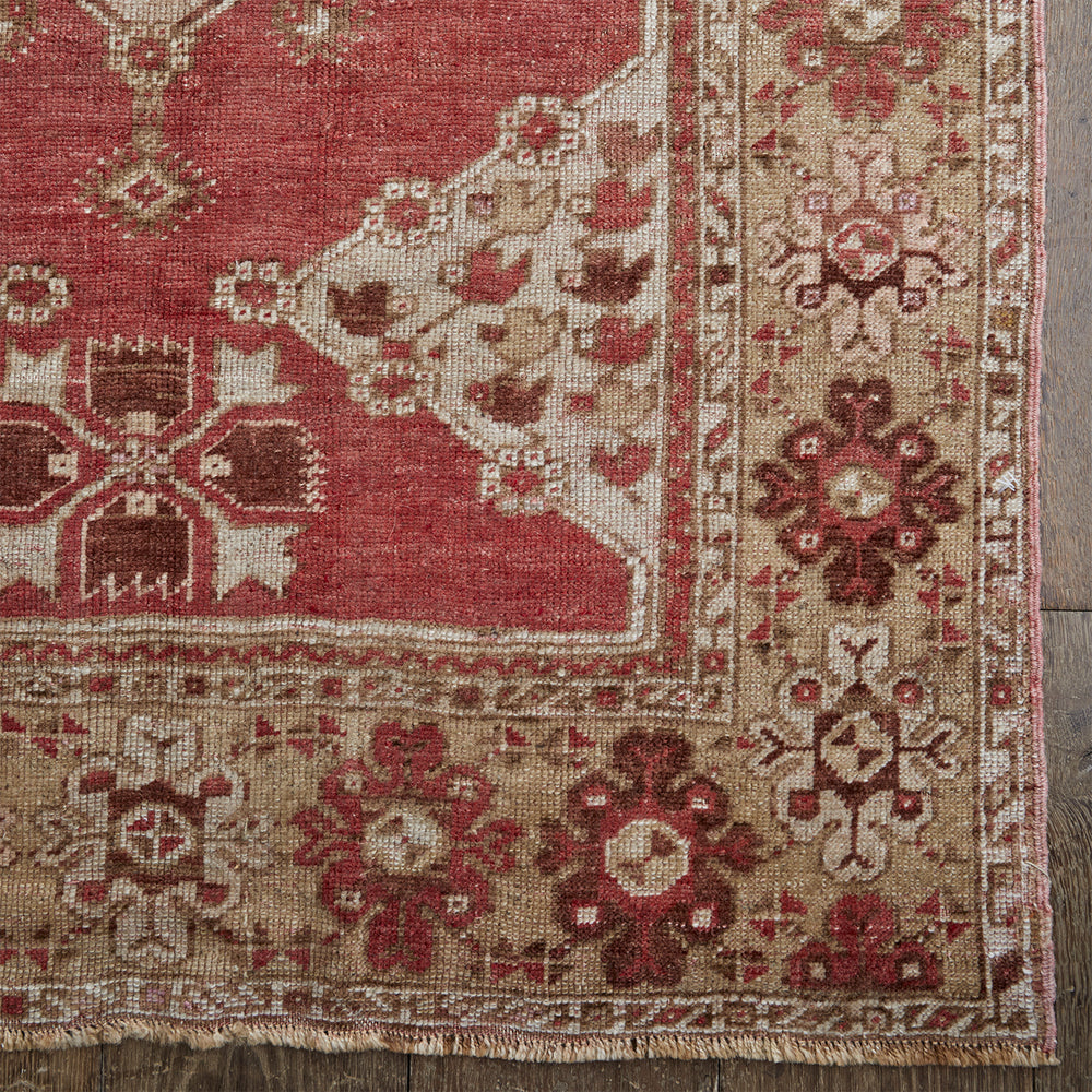 Lemieux et Cie Anatolian Village Rug in coral and tan geometric pattern, vintage Turkish rug corner detail shown on dark wood flooring.