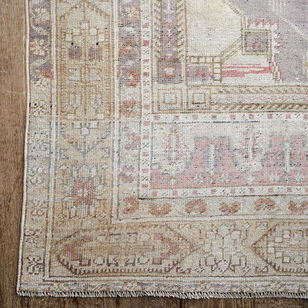 Lemieux et Cie Anatolian Village Rug in soft wool with geometric patterns in blush, tan and grey, vintage Turkish rug on light wood flooring.