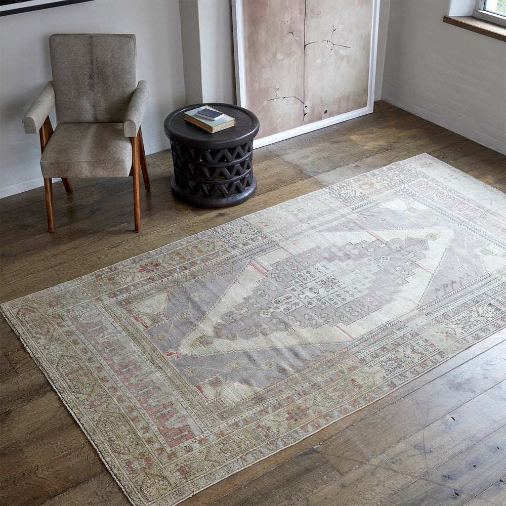 Lemieux et Cie Anatolian Village Rug in soft neutrals with geometric pattern, vintage Turkish wool rug in sitting room with wood floors and upholstered chair.