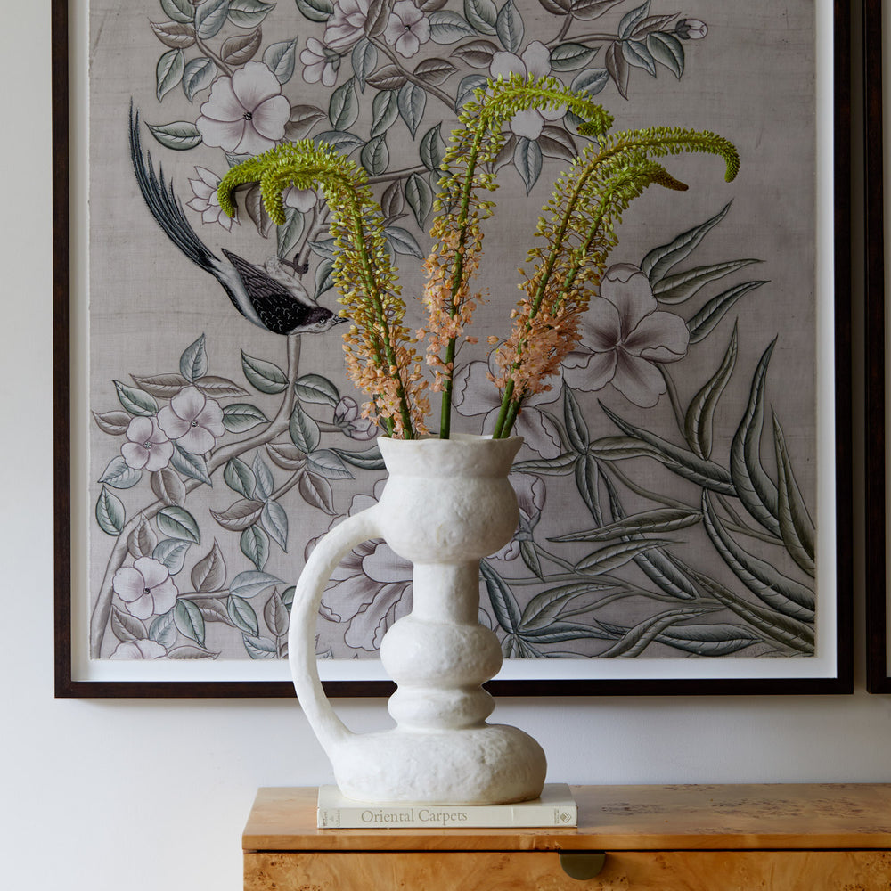 Lemieux et Cie Remi Vase in white, organically sculptural vessel with undulating form, styled on wood surface beneath framed botanical artwork.
