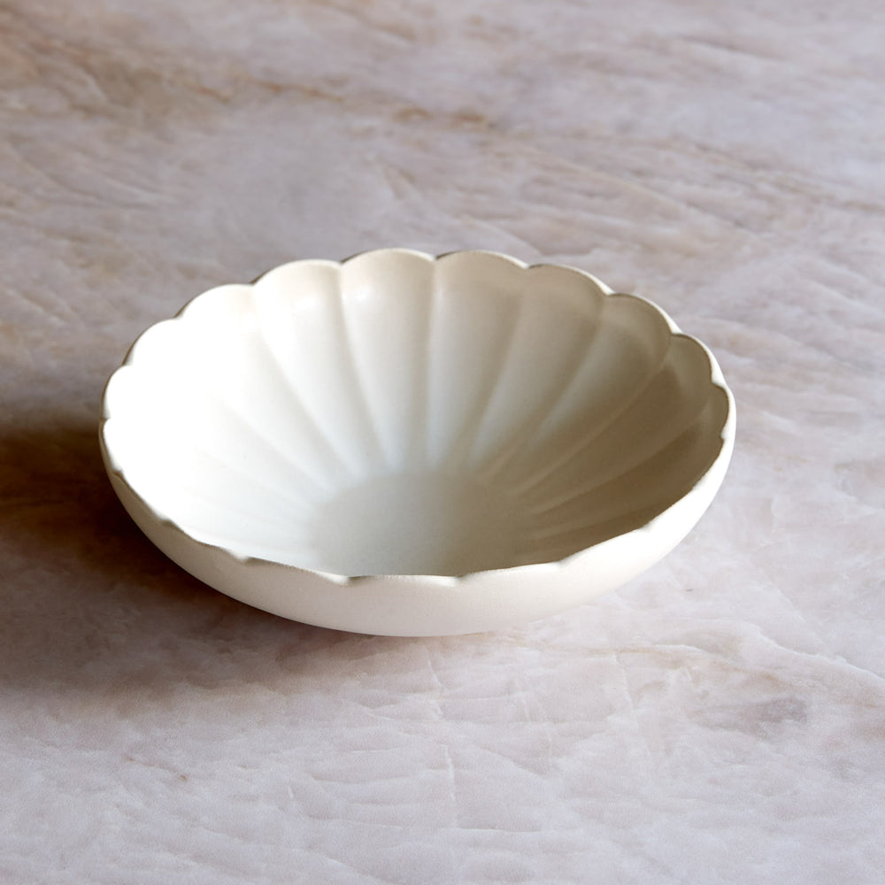 Lemieux et Cie Dhalia Stoneware Pasta Bowl in white, scalloped ceramic bowl with fluted edges, shown on soft neutral stone surface.