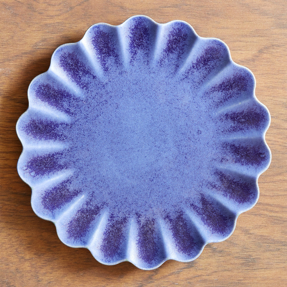 Lemieux et Cie Dhalia Stoneware Dinner Plate in blue with scalloped edges, ceramic plate shown on warm wood surface.