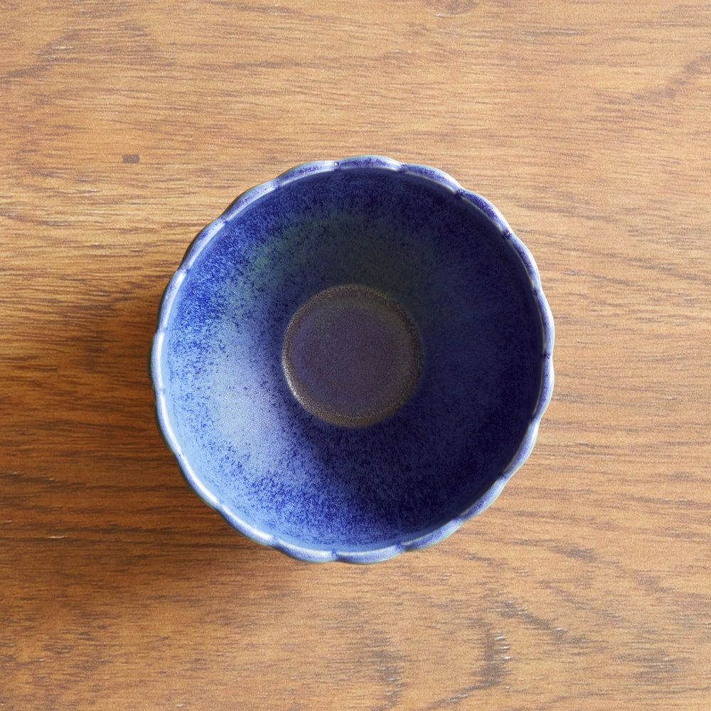 Lemieux et Cie Dhalia Stoneware Bowl in blue with scalloped edges, shown from above on warm wood surface.