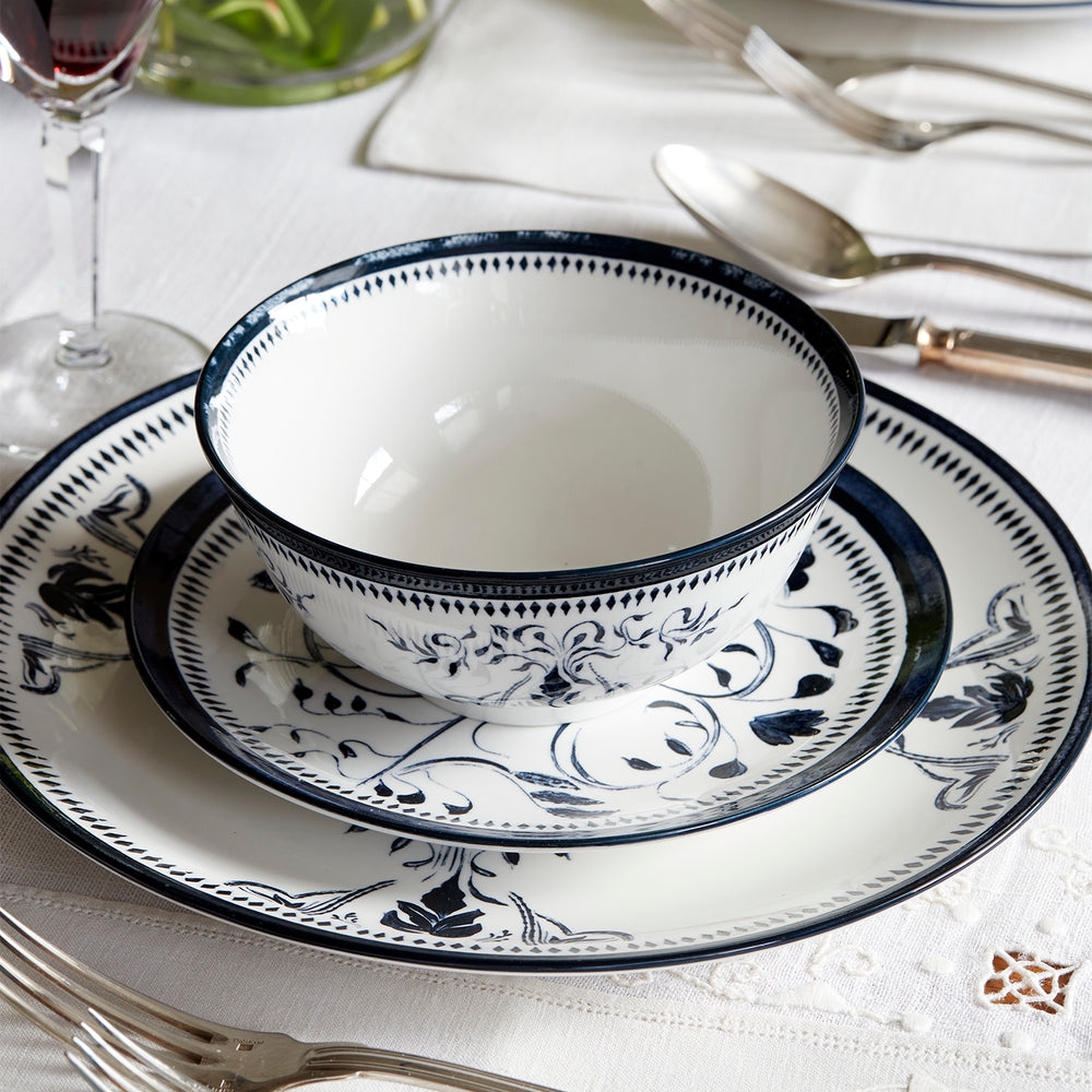 Lemieux et Cie Bruges Porcelain Small Bowl, hand-painted blue and white floral motif on ceramic, shown on white linen tablecloth with flatware and wine glass.