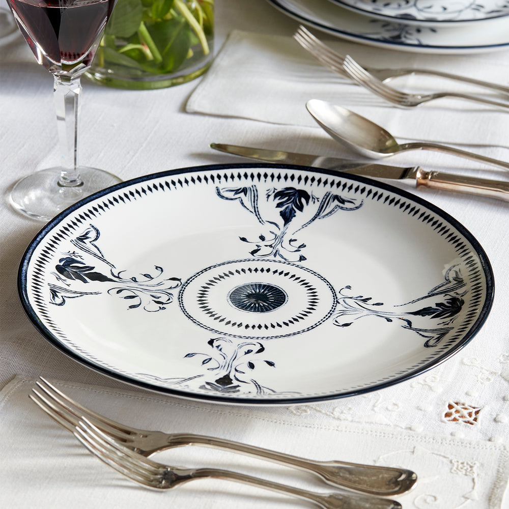 Lemieux et Cie Bruges Porcelain Dinner Plate with hand-painted blue and white floral motifs, set on white linen tablecloth with flatware and glassware.