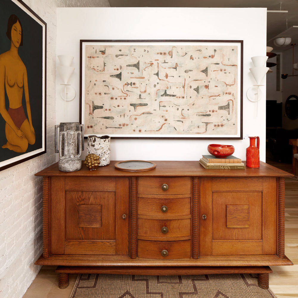 Lemieux et Cie Dubois Coffee Table in warm wood with turned legs and paneled doors, hexagonal form styled against white walls with framed art.