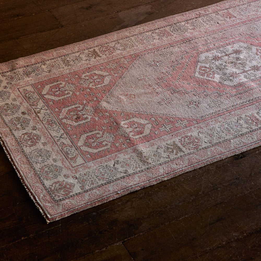 Lemieux et Cie Vintage 1960's Anatolian rug in faded rose and taupe with geometric borders, shown on dark wood flooring.