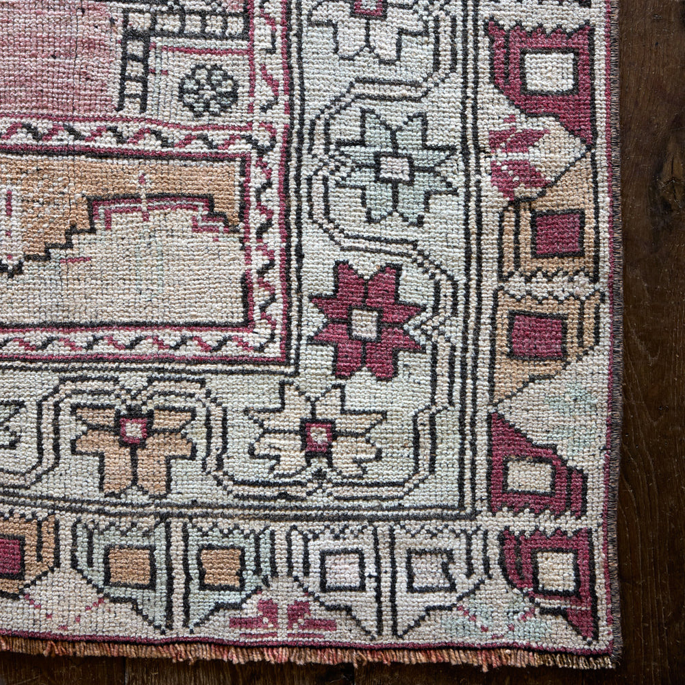 Lemieux et Cie Vintage 1960's Anatolian rug in ivory, burgundy and tan, handwoven carpet with geometric border detail shown on dark wood flooring.