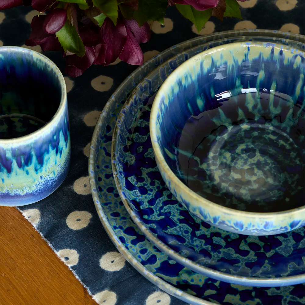 Lemieux et Cie Hanami Stoneware Bowl Set in Indigo, ceramic bowls with reactive glaze, styled on patterned textile with fresh florals and wood table.