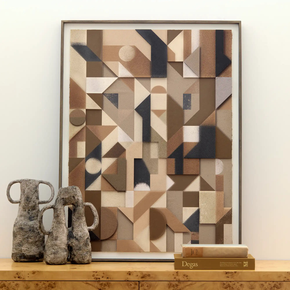 Lemieux et Cie Assemblage Géométrique No. 7, framed geometric artwork in neutral tones of tan, charcoal and cream, styled on wood console with ceramic vessels and books.
