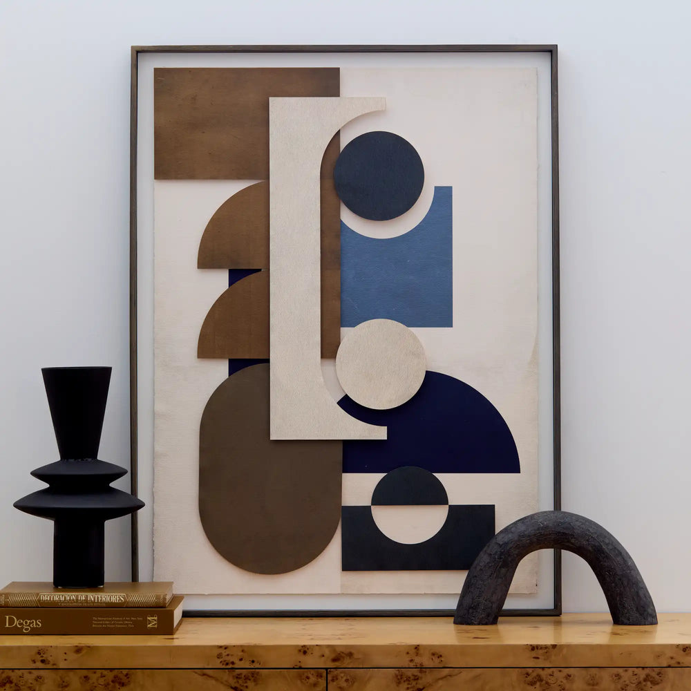 Lemieux et Cie Assemblage Géométrique No. 4, framed geometric artwork in brown, cream, and navy, styled on wood surface with sculptural objects and art books.