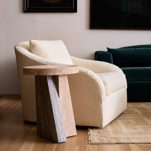 Lemieux et Cie Borel Side Table in walnut, sculptural side table with angled base beside ivory bouclé chair, wood floors and neutral walls.