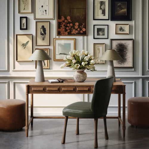 Lemieux et Cie Voltaire Desk in wire-brushed oak, handmade desk with three drawers, shown with green chair and paired lamps in paneled room with gallery wall.
