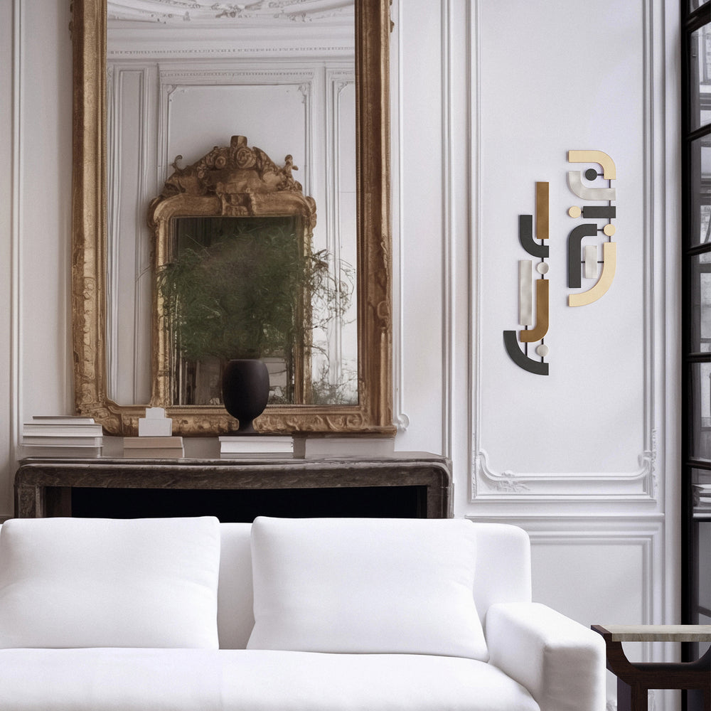 Lemieux et Cie wall sculpture with hand-cut brass geometric shapes in varied finishes, displayed in a sitting room with white paneled walls and ornate mirror.