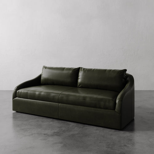 Lemieux et Cie Dark Green Rousseau Leather Sofa on a gray floor with a plain white wall background.