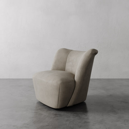 Lemieux et Cie Aurélie Leather Swivel Chair in warm taupe, sculptural rounded form, shown on polished concrete floor against neutral textured walls.