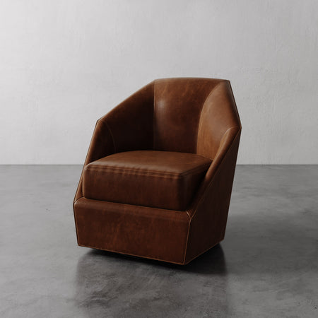 Lemieux et Cie Bijou Swivel Chair in warm cognac leather, sculptural geometric armchair with angular faceted silhouette on concrete floor.