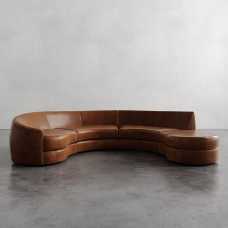 Lemieux et Cie Rulmann 4-Piece Left Sectional in leather, curved modular sofa with organic flowing form, on polished concrete floor with neutral plaster wall.
