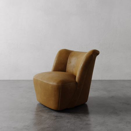 Lemieux et Cie Aurélie Leather Swivel Chair in warm tan leather, sculptural rounded accent chair on polished concrete floor against white walls.