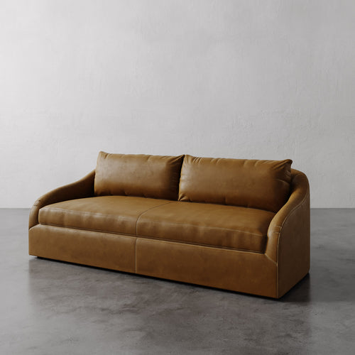 Lemieux Et Cie Chestnut Brown Rousseau Leather Sofa on a gray floor with a plain white wall background