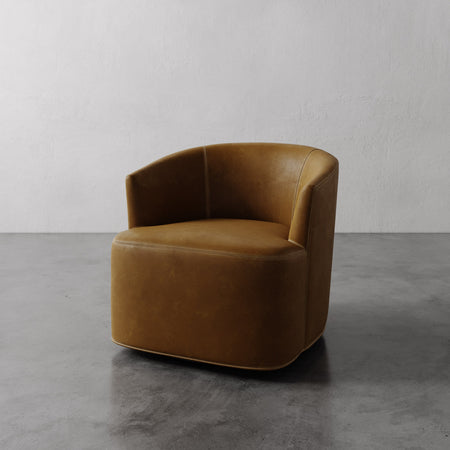 Lemieux et Cie Garnier Swivel Chair in warm tan leather, rounded barrel-back form on concrete floor against neutral plaster wall.