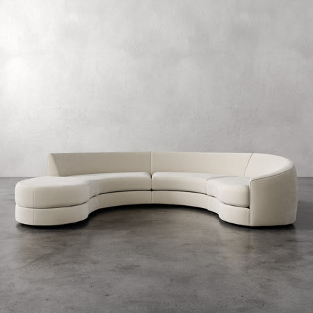 Lemieux et Cie Rulmann 4-Piece Right Sectional in ivory, curved modular sofa shown on polished concrete floor against textured plaster walls.