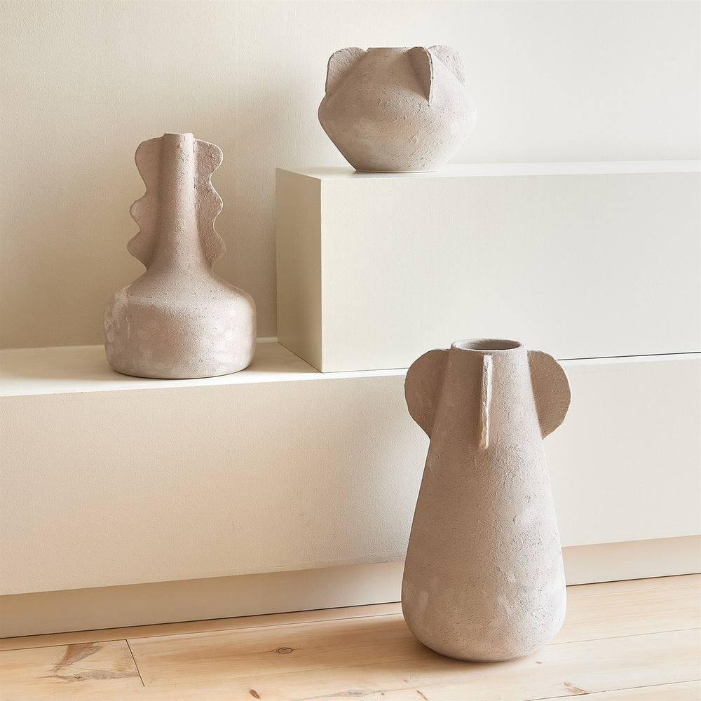 Lemieux et Cie Anouar Vase Collection in buff, sculptural hand-shaped vessels with organic forms, arranged on neutral shelving and wood floor.