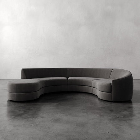 Lemieux et Cie Rulmann 4-Piece Right Sectional, curved modular sofa with sculptural form and low profile, shown on concrete floor against plaster walls.