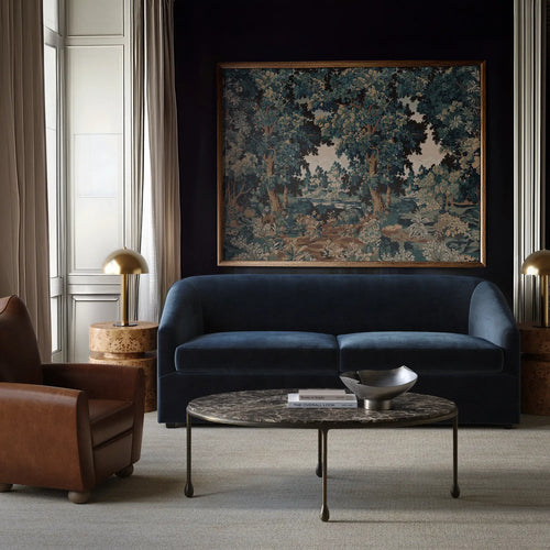 Lemieux et Cie Arvelle Queen Sleeper, curved-arm sofa in deep blue, styled in sitting room with dark walls, marble coffee table, and neutral rug.