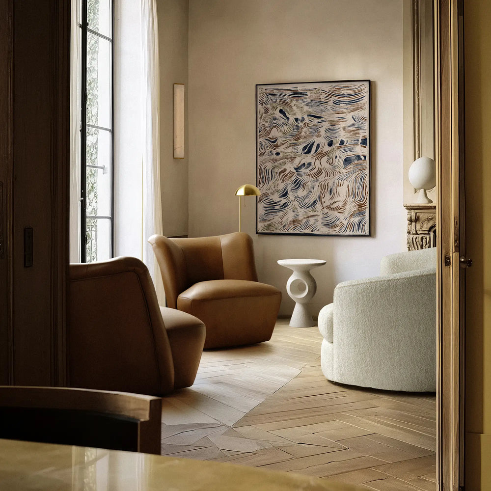 Lemieux et Cie Aurélie Leather Swivel Chair in caramel brown, sculptural rounded form in a sitting room with herringbone wood floors and neutral plaster walls.