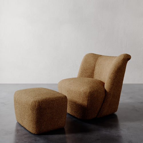 Lemieux et Cie Aurélie Ottoman, rounded sculptural form in warm caramel, paired with matching chair on dark polished floor against neutral walls.